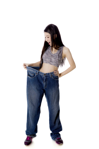 Shocked woman trying her old jeans on studio - Foto, imagen