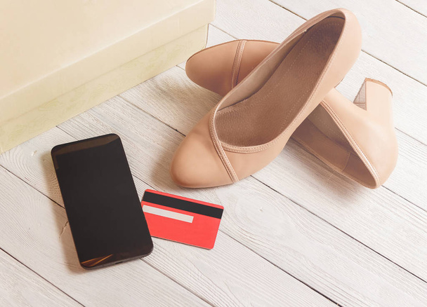 Box, smartphone, credit cards and womans shoes lying on the white wooden background - Foto, Bild