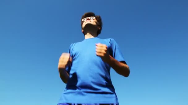 man in turn blue gym suits runs on place before blue sky. type from below - Video