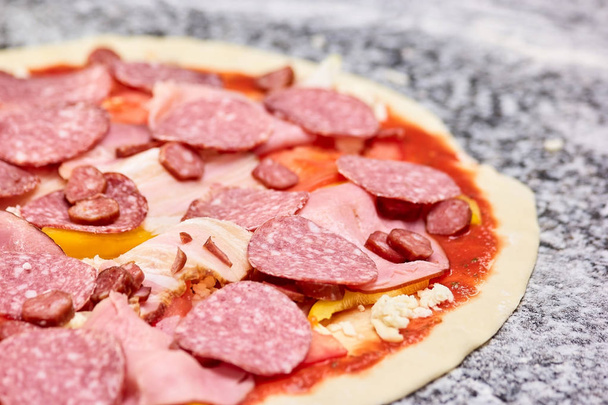Закрыть ломтики колбасы на тесте для пиццы
. - Фото, изображение