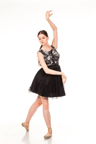 Beautiful young ballerina, isolated on white background. In pointes and black ballet tutu. Sits on the twine, shows different poses.  graceful brunette with long hair. - Φωτογραφία, εικόνα