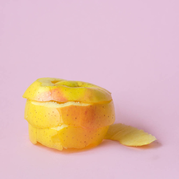 リサイクルのシンボルとしてピンクの背景に黄色のリンゴの皮は、経済を循環させる - 写真・画像