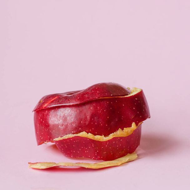 Кожура из красного яблока на розовом фоне как символ переработки циркулирующей экономики
 - Фото, изображение