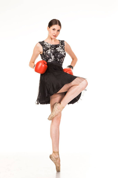 Beautiful young ballerina, isolated on white background. In pointes and black ballet tutu. Shows different poses.  graceful brunette with long hair. posing with boxing gloves  - Photo, Image