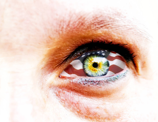 zachte focus en close up van een oog van de groen geel vrouw geïsoleerd op een witte achtergrond met usa vlag in de iris - Foto, afbeelding