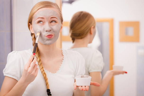 Woman applying with brush clay mud mask to her face - Photo, Image