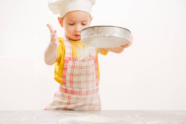 Details of children's hands kneading dough. Cheerful cook child boy in a cap prepares burritos - Photo, image