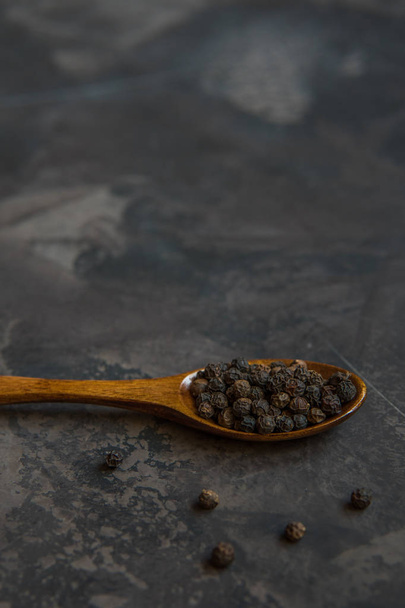 Black pepper on a wooden spoon, copy space - Fotó, kép