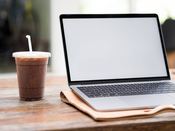 Laptop on wooden desk with iced coffee in the cafe. - Foto, imagen