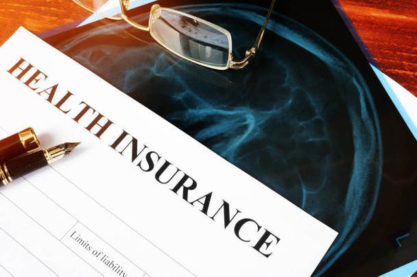 Health insurance policy concept. Claim form and X-ray on a table. - Φωτογραφία, εικόνα