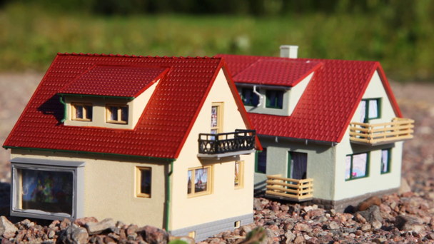 iki küçük oyuncak ev kırmızı çatılar ile park içinde taşlar üzerinde durmak - Video, Çekim