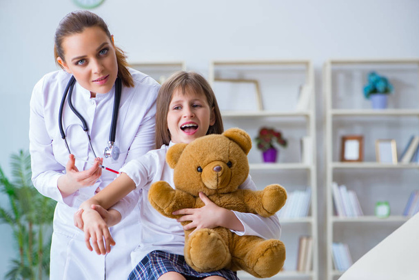 Woman female doctor examining little cute girl with toy bear - Foto, imagen