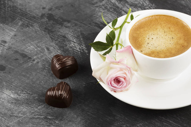 Espresso coffee in a white cup, a pink rose and chocolates on a  - Foto, imagen