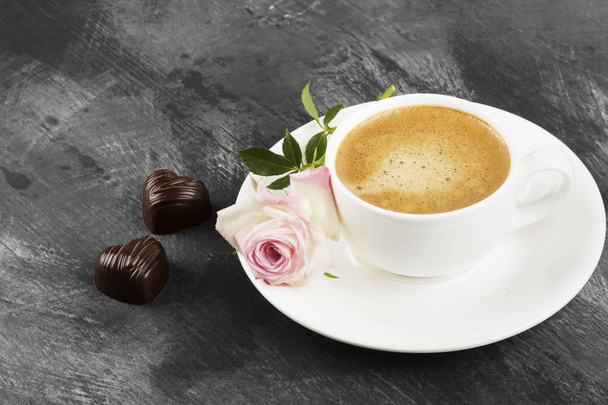 Espresso coffee in a white cup, a pink rose and chocolates on a  - 写真・画像