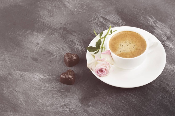 Espresso coffee in a white cup, a pink rose and chocolates on a  - Foto, imagen