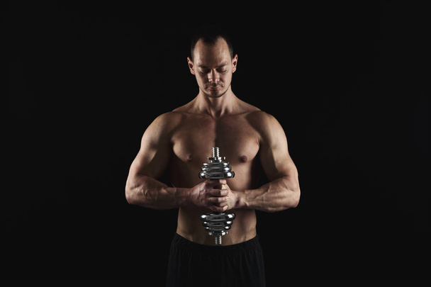 Strong athletic man with dumbbell showes naked muscular body - Фото, зображення