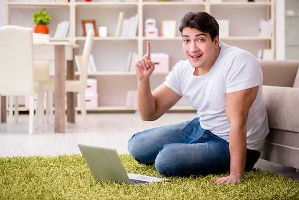 Man working on laptop at home on carpet floor - Foto, Imagen