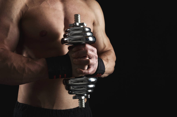 starker athletischer Mann mit Hantel zeigt nackten muskulösen Körper - Foto, Bild