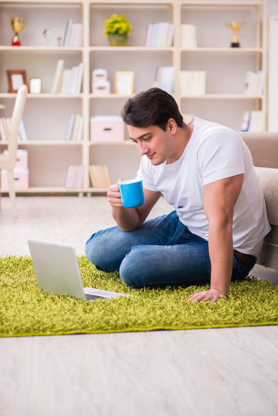 Homme travaillant sur ordinateur portable à la maison sur le plancher de tapis - Photo, image