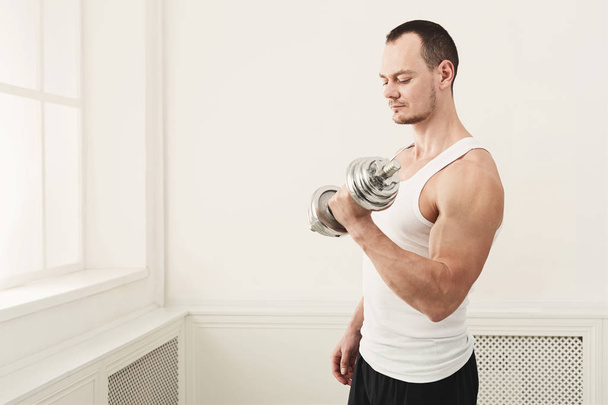 Strong athletic man with dumbbell showes muscular body - Foto, imagen