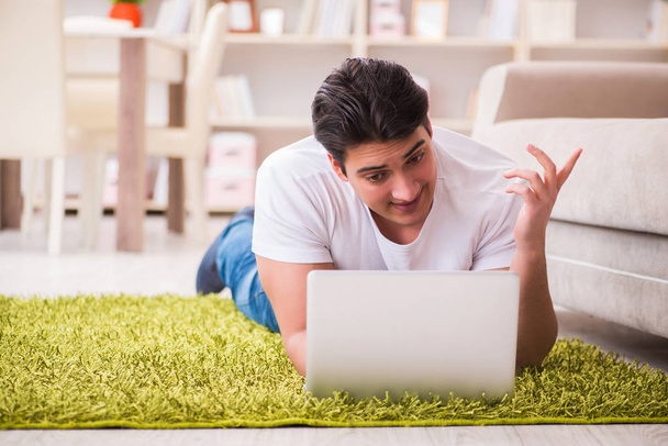 Man werkt op laptop thuis op tapijt vloer - Foto, afbeelding