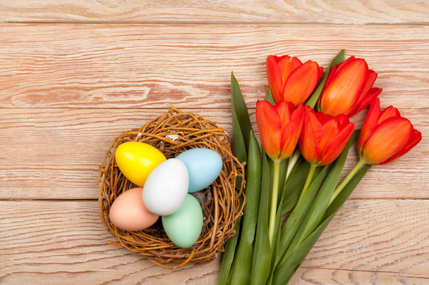 Easter Eggs in a birds nest with colorful tulips - Фото, изображение