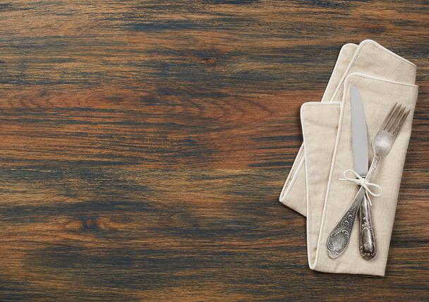 Ніж, виделка і рушник на дерев'яному столі
 - Фото, зображення