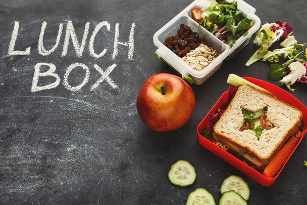 Cajas de almuerzo llenas de comida saludable en pizarra negra
 - Foto, imagen