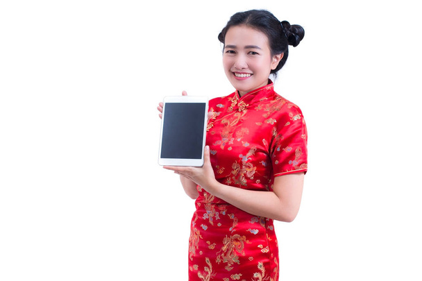Όμορφη νεαρή γυναίκα της Ασίας φορούν φόρεμα κινέζικο παραδοσιακό cheongsam ή qipao. Χέρι που κρατά κενή οθόνη ψηφιακή δισκίο. απομονωμένα σε λευκό φόντο, αγοράζοντας ψηφιακή έννοια σε απευθείας σύνδεση, τεχνολογία. - Φωτογραφία, εικόνα