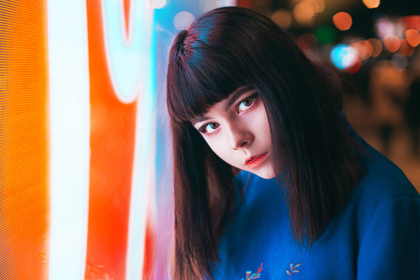 Young Japanese girl stand near neon lights and pose to the camer - Foto, afbeelding