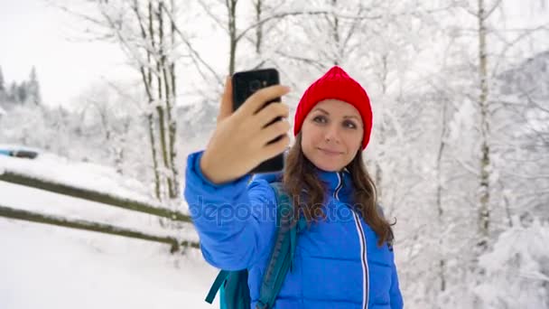 Mujer joven utiliza un teléfono inteligente para hacer fotos selfies en el fondo de una hermosa vista de las montañas, Cárpatos
 - Imágenes, Vídeo