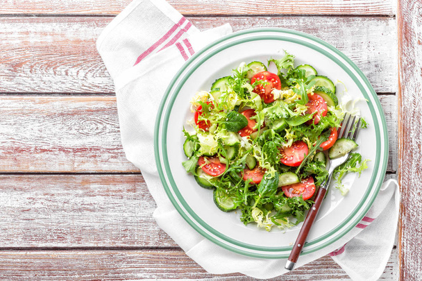 Salada vegetal saudável de tomate fresco, pepino, espinafre, friso e arugula na chapa. prato vegan. vista superior
 - Foto, Imagem