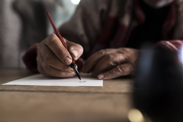 Ένας άνθρωπος με βρώμικα χέρια, γράφοντας σε ένα φύλλο χαρτιού  - Φωτογραφία, εικόνα