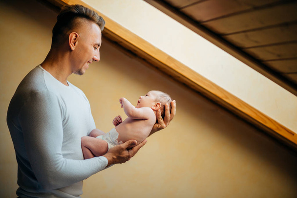 Father Holding Newborn Baby At Home near window - Valokuva, kuva