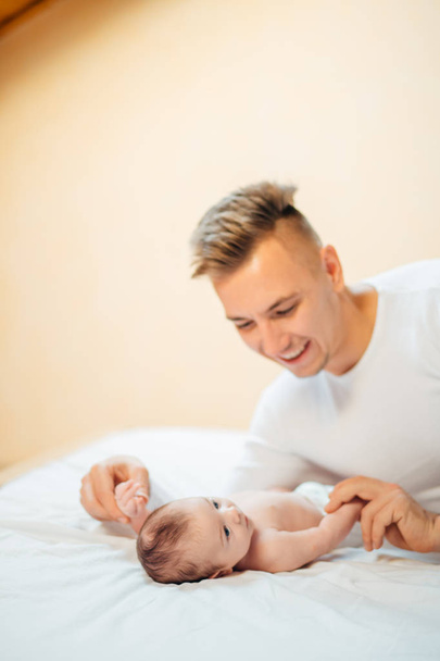 Father lying on bed and holds his baby - Foto, Bild