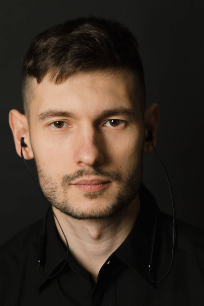 Man in headphones and black shirt on a black background - Photo, Image