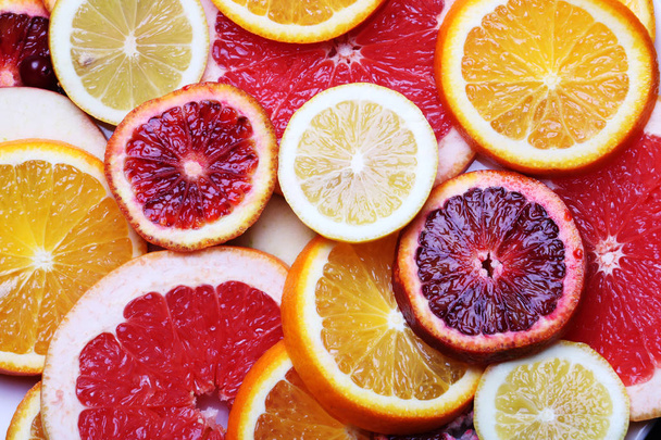 Sliced citrus fruits, vitamins, oranges, grapefruits, lemons, juicy fruits background - Photo, Image
