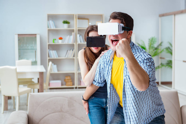 Νεαρή οικογένεια παίζει παιχνίδια με γυαλιά εικονικής πραγματικότητας - Φωτογραφία, εικόνα