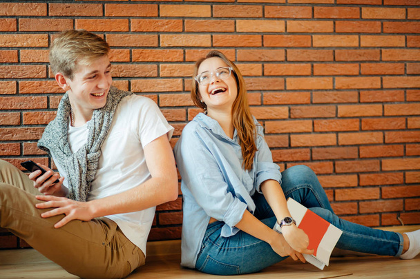 Couple students sitting outside classroom and studying together - Фото, изображение