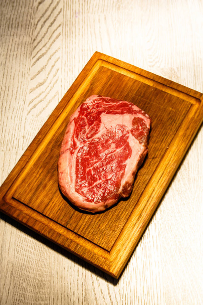 Raw ribeye steak lying on the Board. - Foto, Imagen
