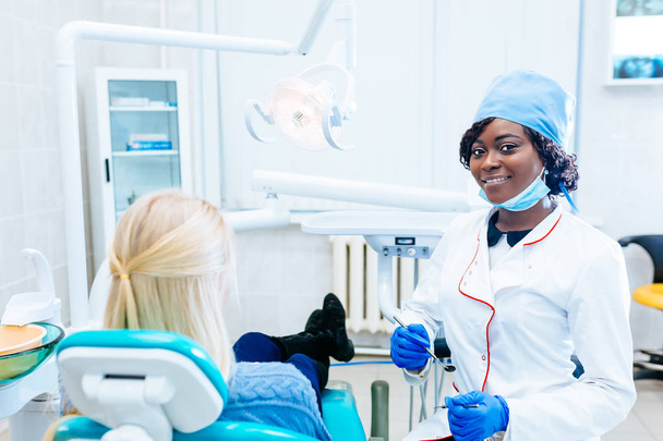 Afro-amerikai női fogorvos kezelése beteg klinikán. Fogászati klinika koncepció. - Fotó, kép