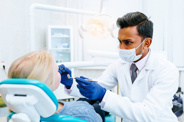 jeune dentiste asiatique confiant Traitement médical à une patiente à la clinique. Concept de clinique dentaire
. - Photo, image