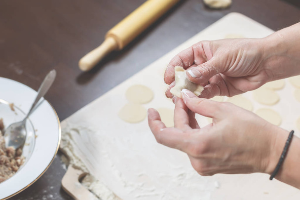 Mãos femininas moldam bolinhos caseiros no fundo de uma mesa de madeira
 - Foto, Imagem