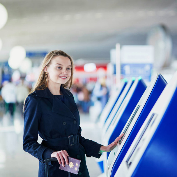 Młoda kobieta w międzynarodowy port lotniczy robi samodzielnego zameldowania - Zdjęcie, obraz