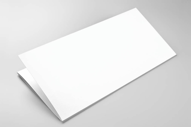 Hoja de papel o membrete plegado en blanco sobre fondo gris
 - Foto, imagen