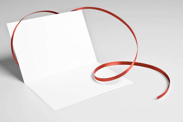 赤いリボンで飾られた空白 4 つ折りカード  - 写真・画像