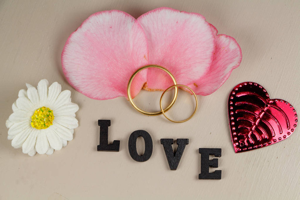 Dos anillos de boda en oro, pétalos, corazón, flor y amor
 - Foto, imagen
