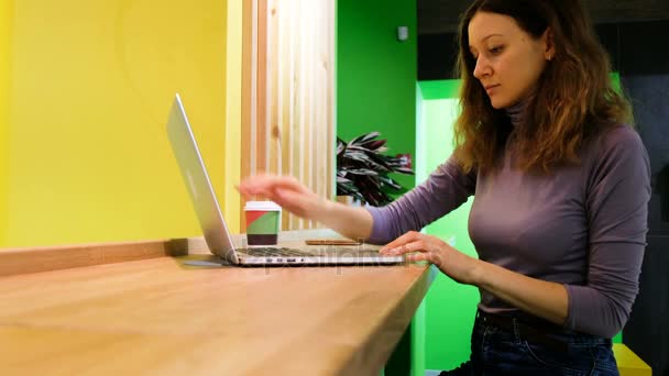 A kávézókban kaukázusi lány megnyílik egy laptop, és iszik kávét, szabadúszóként dolgozik egy kávézóban, 4k. - Felvétel, videó