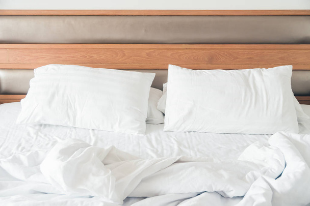 Travesseiro branco com decoração de cama enrugada no interior do quarto
 - Foto, Imagem