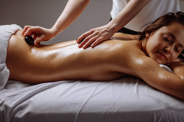 woman getting hot stone massage in spa salon. Beauty treatment concept - Fotoğraf, Görsel